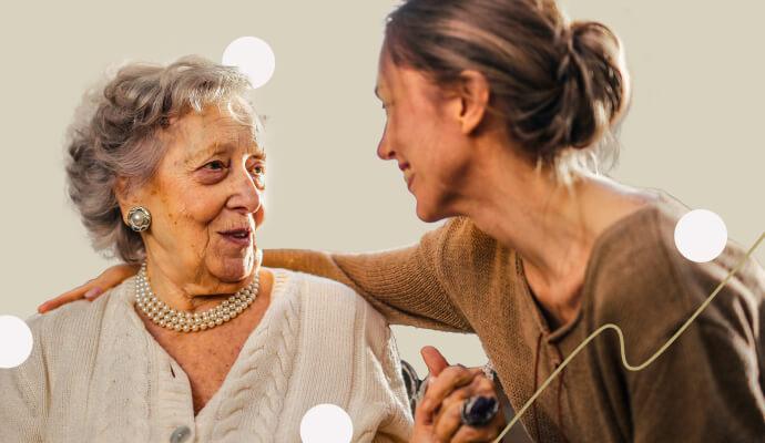 A young woman and an old woman look at each other smiling.