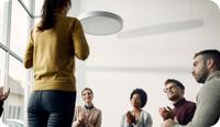 A female therapist stands and uses group therapy icebreaker questions with her therapy group of four adults