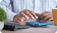 A clinician's hands type on a calculator as they determine how much money they are making in private practice