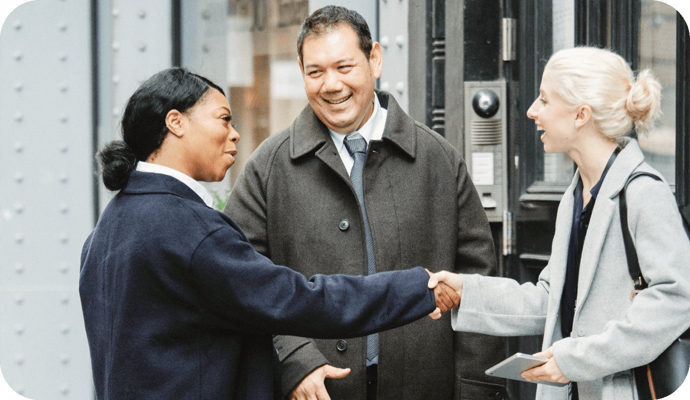 Three people stand out on a street greeting each other as unconventional referral partners