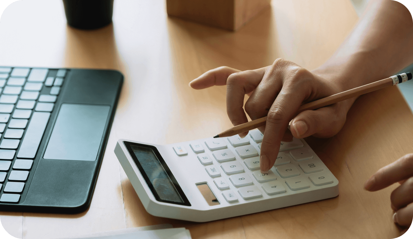 A therapist's hand types on a calculator and a laptop as they create their private practice budget