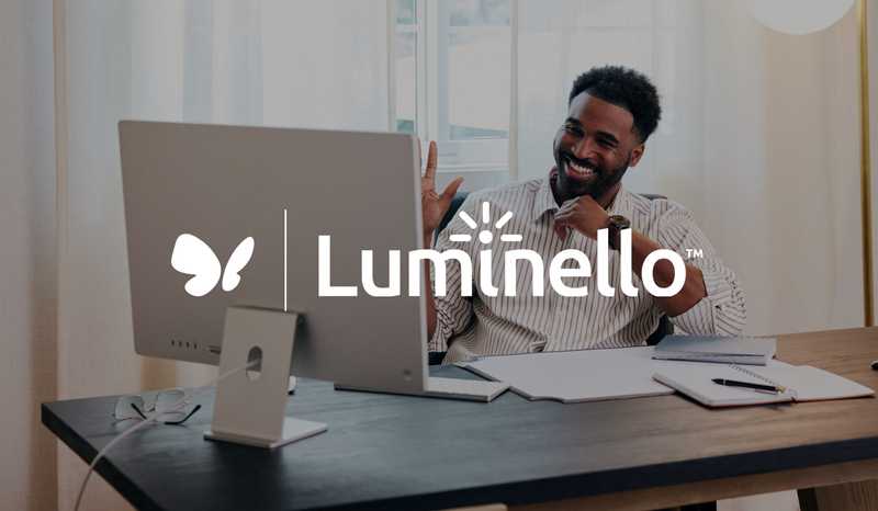 Man smiles and waves at his computer with SimplePractice and Luminello logos
